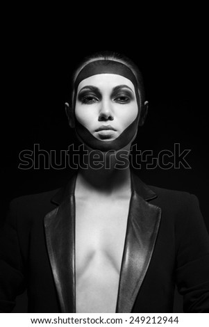 black and white portrait of a beautiful woman with face art of a black mask in a jacket