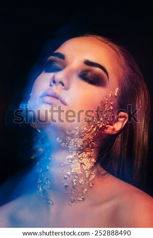 portrait of beautiful girl with gold on his face, made in mixed light, ice and fire