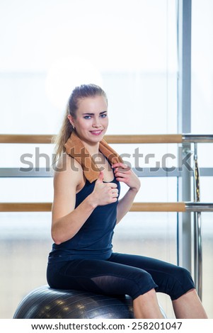 Beautiful young woman girl after physical excercise in fitness center gym  sitting on gymnastics ball.