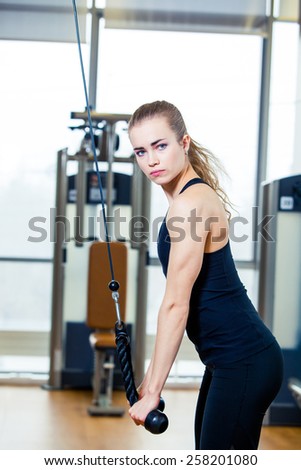 sport. fitness, lifestyle and people concept - young woman flexing muscles on gym machine