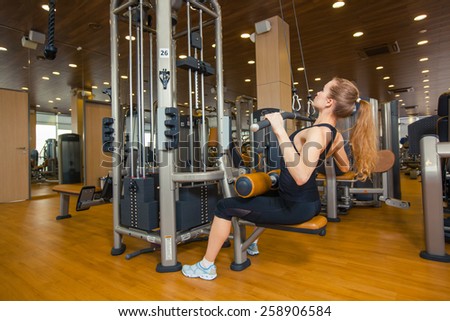 sport, fitness. lifestyle and people concept - young woman flexing muscles on gym machine