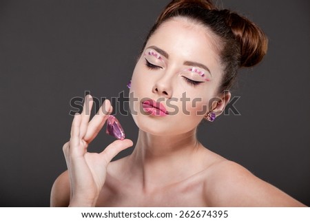 Young beautiful woman with perfect makeup, drawing bows, admiring the gem.
