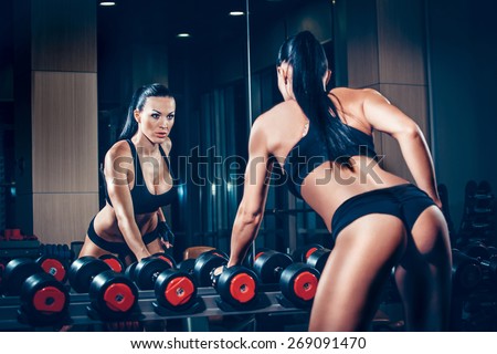 sexy young girl resting after dumbbells exercises. Fitness woman  resting in gym.