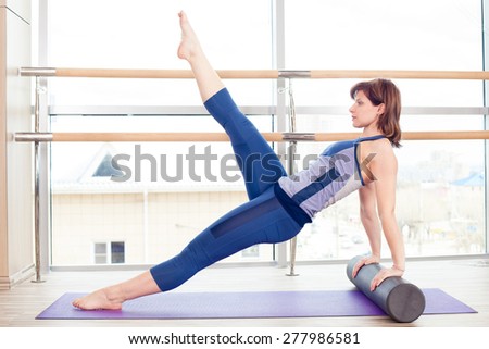 fitness, sport, training and lifestyle concept -  woman doing pilates on the floor with foam roller