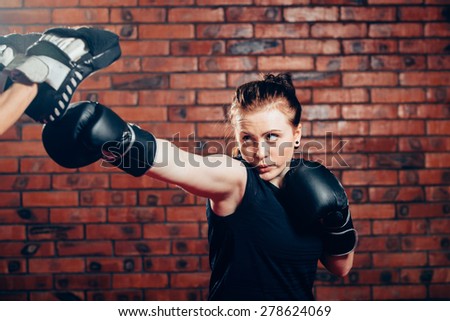 Young female in 20s boxing on a punching bag.