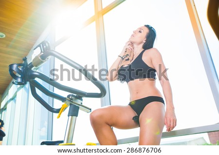 Beautiful woman at the gym on bike, cycle, sunny gym, general plan, weary