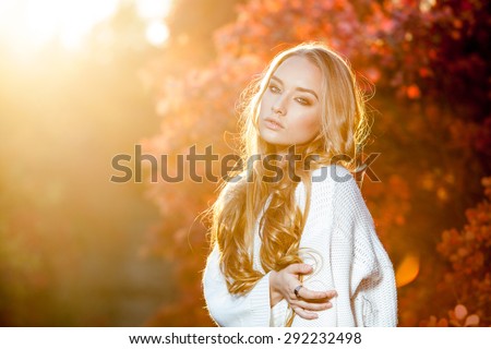 young woman on a background of red and yellow autumn leaves with beautiful curly hair