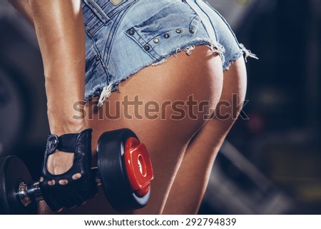 Athletic young woman doing a fitness workout with weights. buttocks close-up.