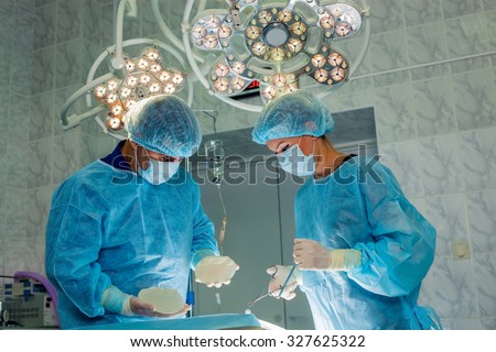 Surgeons team working with Monitoring of patient in surgical operating room. breast augmentation.