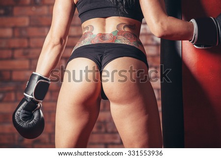 Young sexy girl with boxing gloves. punching bag, on the background wall of red brick.