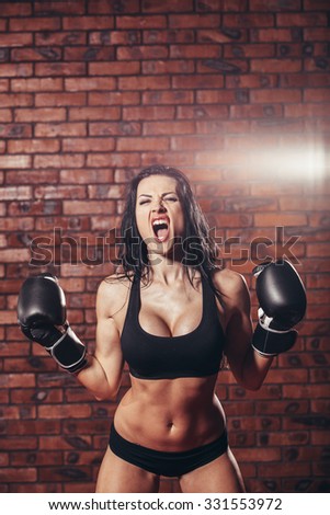 Young sexy girl with boxing gloves, on the background wall of red brick