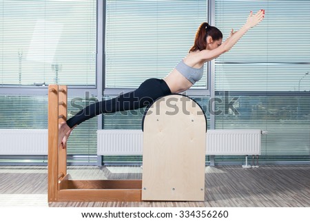 Pilates, fitness, sport, training and people concept - smiling woman doing  exercises on ladder barrel.