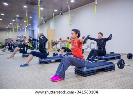 Sport, fitness, lifestyle and people concept - group flexing muscles with barbells in gym.