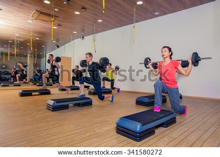 Sport, fitness, lifestyle and people concept - group flexing muscles with barbells in gym.