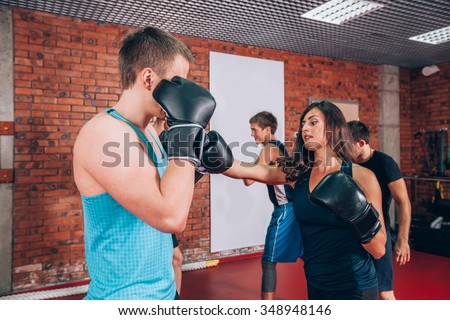 Boxing aerobox group with personal trainer man at fitness gym, gloves, punching bag.