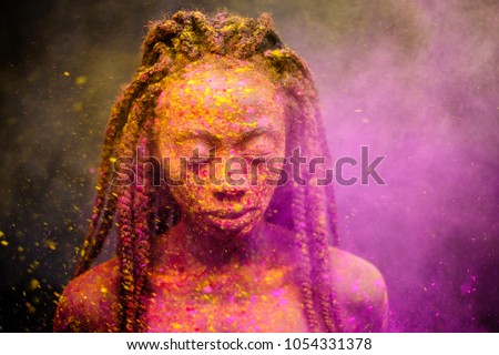 African woman with colourful powder on her face and body.