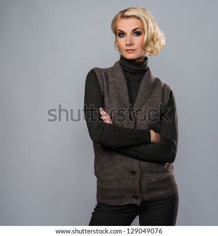 Elegant blond woman in casual brown clothes isolated on grey background