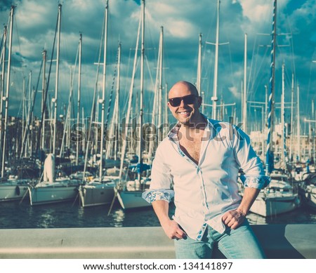 Happy middle-aged man in shirt against yacht port