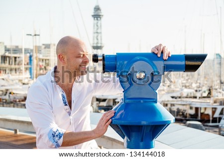 MIddle-aged man looking through telescope over city panorama