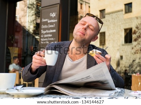 MIddle-aged man enjoying coffee with piece of cake in street cafe