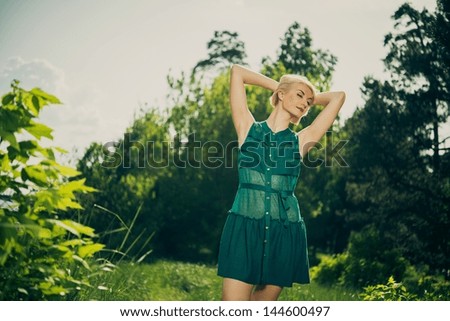 Beautiful blond woman in green dress outdoors