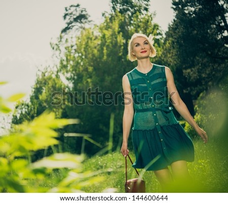 Beautiful blond woman with red bag in green dress outdoors