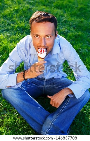 Happy handsome middle-aged man eating ice- cream outdoors