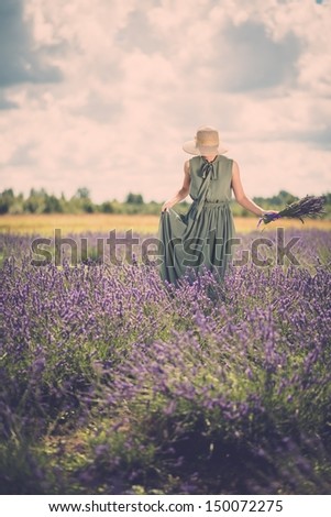 Woman in long green dress and hat in a lavender field