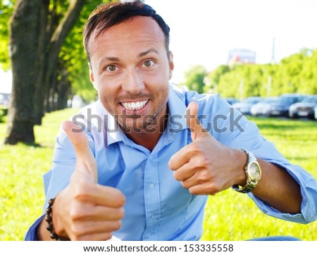 Happy handsome middle-aged man showing thumbs up outdoors