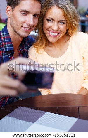 Young couple taking picture of themselves in summer cafe