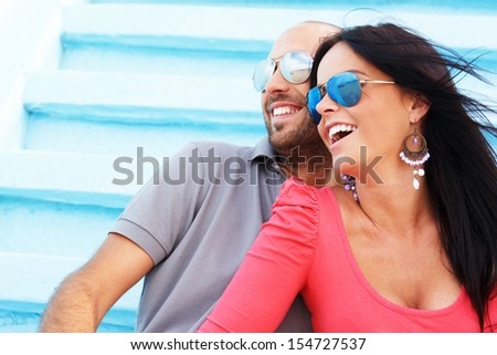 Happy smiling middle-aged couple with beach reflected in sunglasses