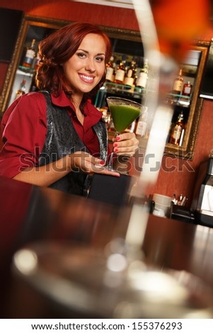 Cheerful barmaid with cocktail behind bar counter