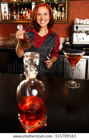 Beautiful redhead barmaid with bottle behind bar counter