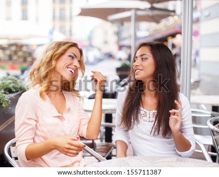 Two beautiful girls chatting in summer cafe