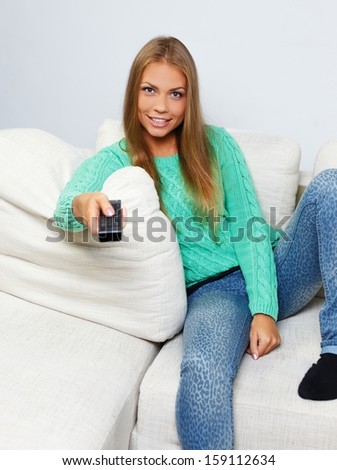 Young beautiful woman on a sofa with remote control