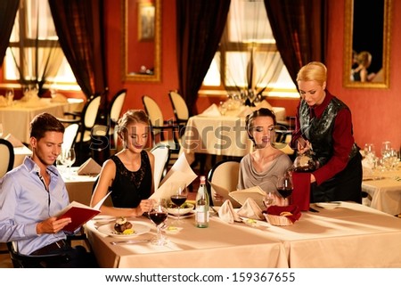 Group Of Young Friends With Menus Choosing In A Luxury Restaurant