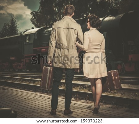 Beautiful vintage style couple with suitcases on  train station platform