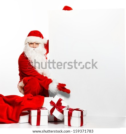 Santa Claus with sack full of gift boxes and blank notice board