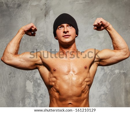 Handsome man with muscular torso in beanie hat posing