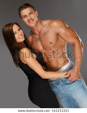 Young woman embracing man with naked muscular torso