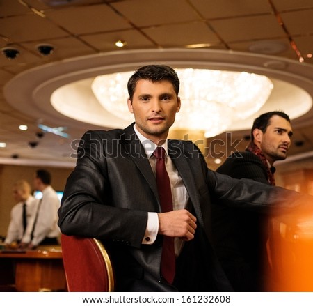 Two young men in suits behind table in a casino