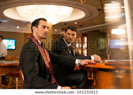 Two young men in suits behind table in a casino