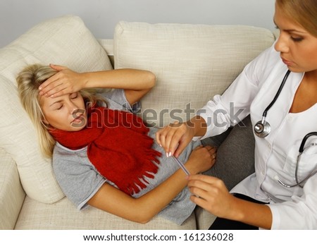 Sick young woman and doctor looking at thermometer