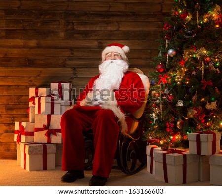 Santa Claus sitting on rocking chair in wooden home interior with gift boxes around him