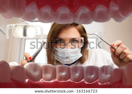 View at young female dentist with dental tools from patient\'s mouth
