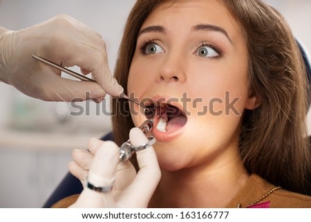 Dentist making anaesthetic injection to scared female patient