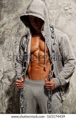 Sporty muscular man in grey hoodie with heavy metal chain