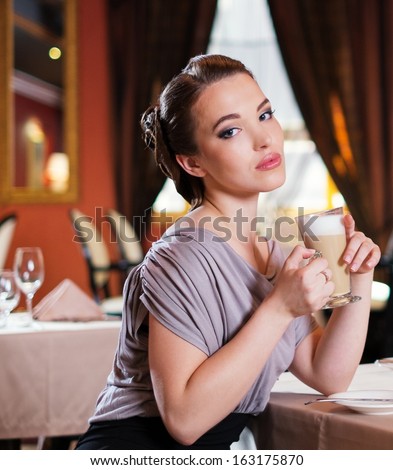 Beautiful young girl with cup of coffee alone in a restaurant