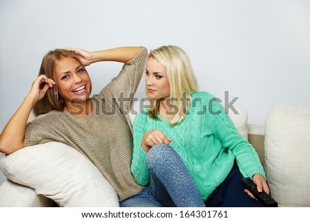 Two young women chatting while sitting on a sofa