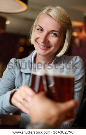 Young woman with beer toasting in a pub